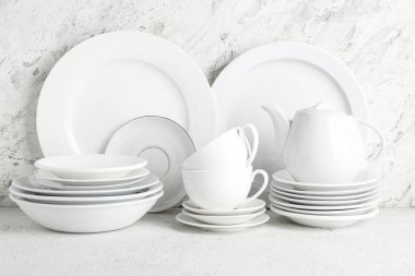 Beyaz masada temiz tabak, fincan, çaydanlık ve çay tabakları var.