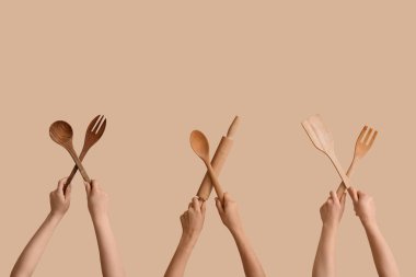 Bej arka planda ahşap mutfak aletleri olan kadın eller.