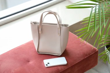 Odadaki yumuşak bankta çantalı cep telefonu.