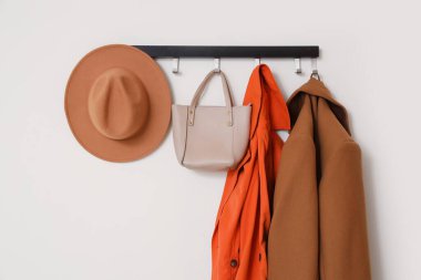 Koridordaki beyaz duvarda asılı duran sonbahar paltoları, çanta ve şapkalarla dolu raflar.