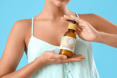 Mavi arka planda hindistan cevizi yağı olan güzel genç kadın, yakın plan.