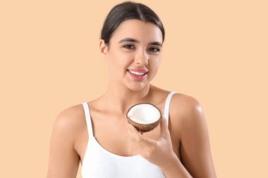 Bej arka planda hindistan cevizi olan güzel genç bir kadın.