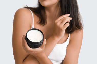 Güzel genç bir kadın evde saçına hindistan cevizi yağı sürüyor, yakın plan.