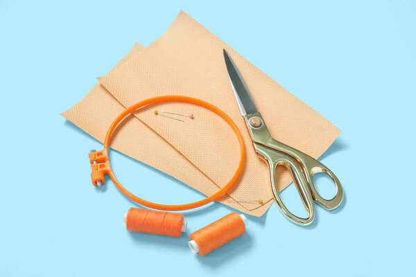 Кольцо для вышивки с холстами, ножницами и нитками на синем фоне