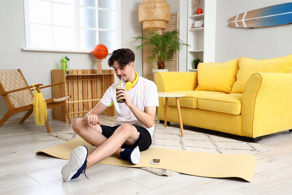 Sporty young man with healthy smoothie at home