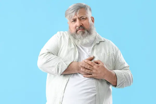 stock image Senior man having heart attack on blue background