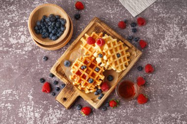 Gri arka planda böğürtlen ve akçaağaç şurubuyla lezzetli waffle tahtaları.