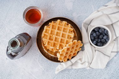 Beyaz arka planda yaban mersinli ve akçaağaç şuruplu lezzetli waffle tabakları.