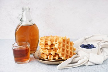 Beyaz arka planda yaban mersinli ve akçaağaç şuruplu lezzetli waffle tabakları.