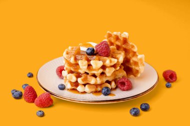 Böğürtlenli lezzetli waffle tabağı ve sarı arka planda akçaağaç pekmezi.
