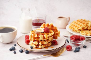 Böğürtlenli waffle, akçaağaç şurubu ve beyaz arka planda bir fincan kahve.