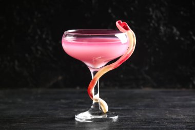 Cadılar Bayramı kutlaması için siyah arka planda bir bardak lezzetli pembe kokteyl ve şeker.