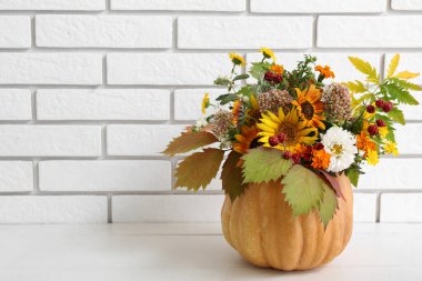 Balkabağında güzel bir sonbahar buketi Masada beyaz tuğla duvara karşı