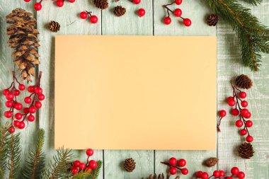 Boş kartıyla güzel bir Noel kompozisyonu, köknar dalları ve yeşil ahşap arka planda meyveler