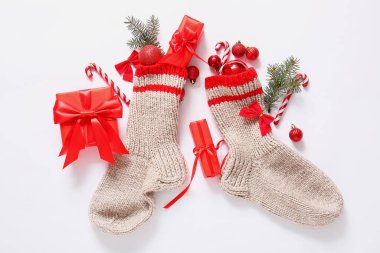 Ağaç dalları, toplar ve beyaz arka planda hediye kutuları olan Noel çorapları.