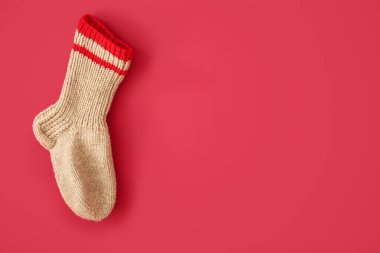 Kırmızı arka planda Noel çorabı asılı.