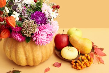 Balkabağı ve tabakta güzel bir sonbahar buketi ve turuncu arka planda taze meyveler.