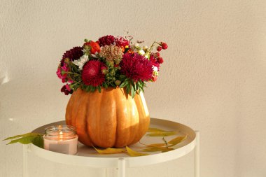 Balkabağında güzel bir sonbahar buketi yaprakları ve yanan bir mumla beyaz arka planda.