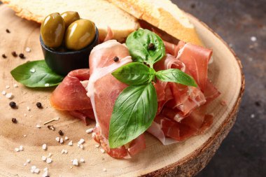 Kahverengi arka planda lezzetli prosciutto dilimleri olan ahşap tahta tahta.