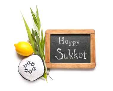 Dört tür (lulav, hadas, arava, etrog) ve beyaz arkaplanda Mutlu SUKKKOT yazılı kara tahta