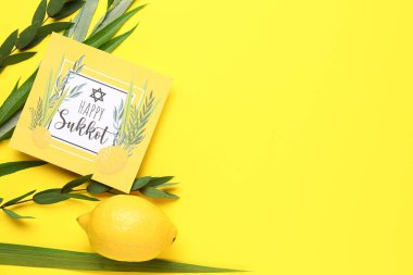 Dört tür (lulav, hadas, arava, etrog) ve sarı arkaplanda Mutlu SUKKKOT yazılı tebrik kartı