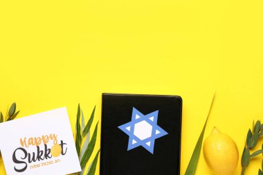Dört tür (lulav, hadas, arava, etrog), Torah ve sarı arkaplanda Mutlu SukKOT yazılı tebrik kartı