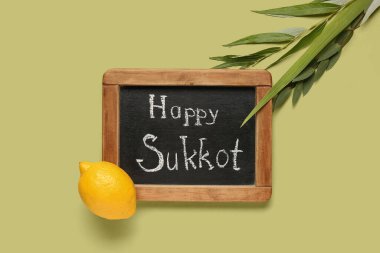 Dört tür (lulav, hadas, arava, etrog) ve yeşil arkaplanda Mutlu SUKKKOT yazılı kara tahta
