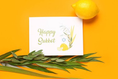 Dört tür (lulav, hadas, arava, etrog) ve turuncu arka planda Mutlu SUKKKOT yazılı tebrik kartı