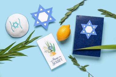 Dört türün (lulav, hadas, arava, etrog) yer aldığı Sukkot festivali kompozisyonu, Tevrat ve mavi zemin üzerindeki tebrik kartı