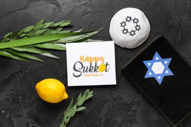 Dört tür (lulav, hadas, arava, etrog), Torah ve siyah grunge arka planda Mutlu SUKKOT yazılı tebrik kartı