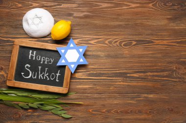 Dört tür (lulav, hadas, arava, etrog), kağıt David yıldızı ve tahta zemin üzerinde Mutlu SUKKOT yazılı karatahta