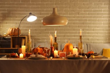 Akşamki Şükran Günü için yanan mumlar, balkabakları ve tebrik kartları olan şenlik masası.