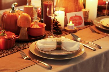 Şükran Günü yemeği için yanan mumlar, balkabakları ve katlanmış peçeteli şenlik masası, yakın plan.