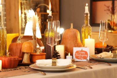 Akşamki Şükran Günü yemeği için yanan mumlar, balkabakları ve tebrik kartları olan güzel bir masa.