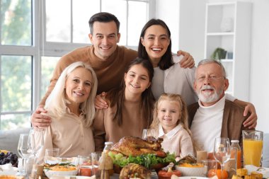 Şükran Günü 'nde mutlu bir aile şenlik masasında yemek yiyor.