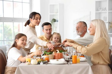 Şükran Günü 'nde mutlu bir aile şenlik masasında yemek yiyor.