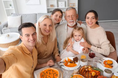 Şükran Günü 'nde şenlik masasında selfie çeken mutlu bir aile.