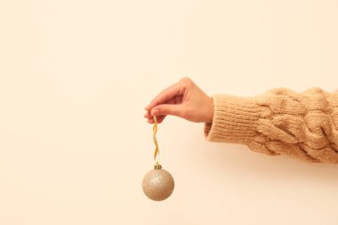 Bej arka planda Noel toplarını tutan kadın.