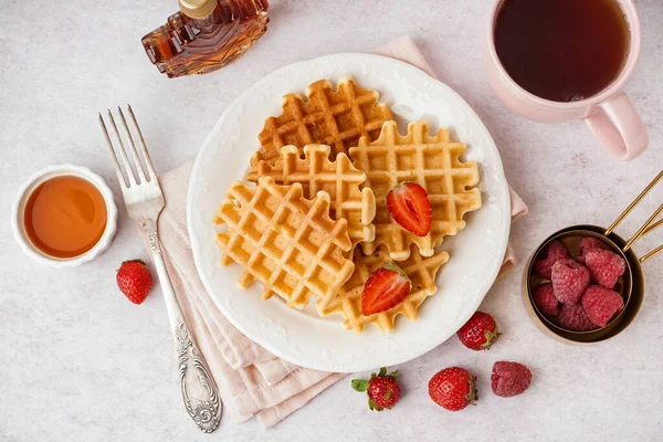 Böğürtlenli waffle, akçaağaç şurubu ve beyaz arka planda bir fincan çay.