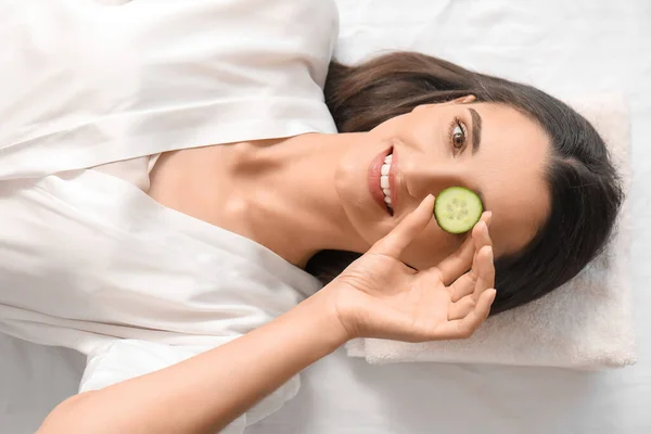 Young woman with cucumber slice in spa salon, top view