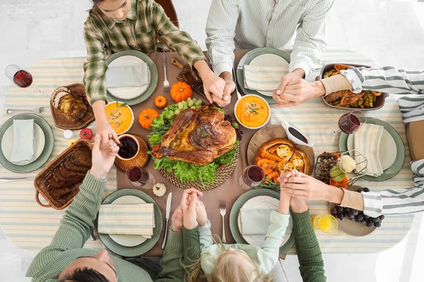 Happy family praying before dinner at festive table on Thanksgiving Day, top view