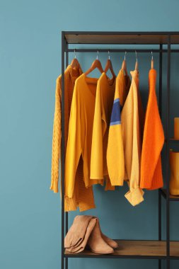 Giysileri ve ayakkabıları mavi duvara yakın raflarda.