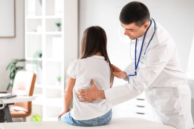 Doktor klinikteki küçük kızın duruşunu kontrol ediyor.