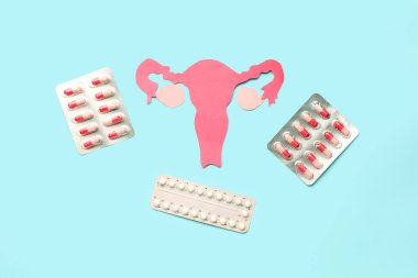 Mavi arka planda hormonal hapları olan kağıt rahim.
