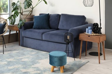 Işıl ışıl oturma odasının içi. Mavi koltuğu, koltuğu ve çiçekleri var.