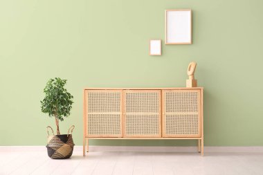 Çağdaş çekmeceler ve yeşil duvarda asılı boş resimler.