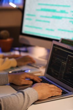 Gece ofiste dizüstü bilgisayarla çalışan erkek programcı, yakın plan.