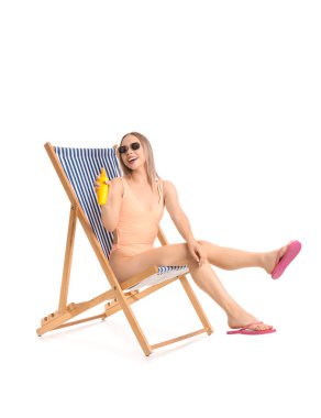 Güneş kremi sürmüş güzel genç bir kadın beyaz arka planda iskemlede oturuyor.