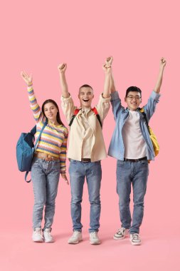 Pembe arka planda sırt çantalı mutlu öğrenciler.