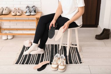Koridorda ortopedik tabanlı ve ayakkabılı bir kadın var.